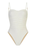 off- white sculpting one-piece swimsuit with removable straps, tummy-shaping design, and body-colored lining on a beach background.