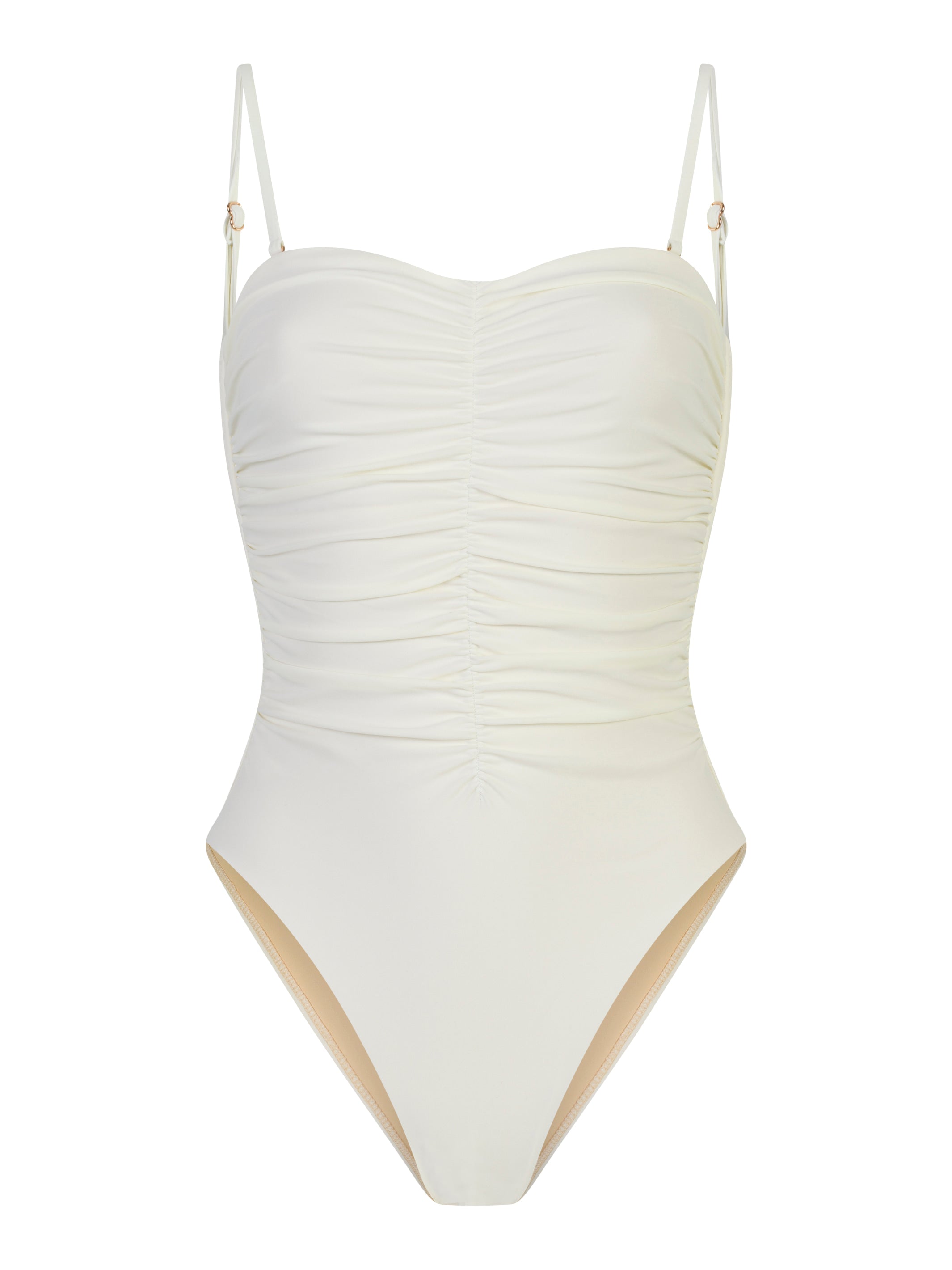 off- white sculpting one-piece swimsuit with removable straps, tummy-shaping design, and body-colored lining on a beach background.